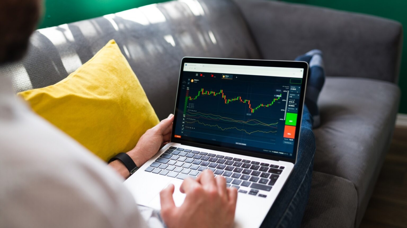 Trading finances. Young man resting on the couch while checking the stock market on the laptop