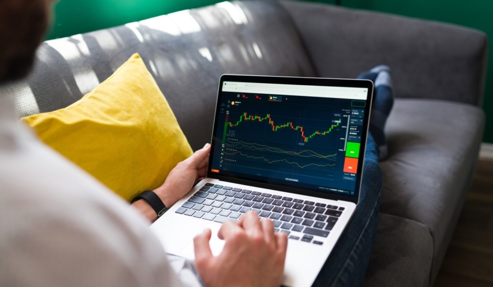 Trading finances. Young man resting on the couch while checking the stock market on the laptop
